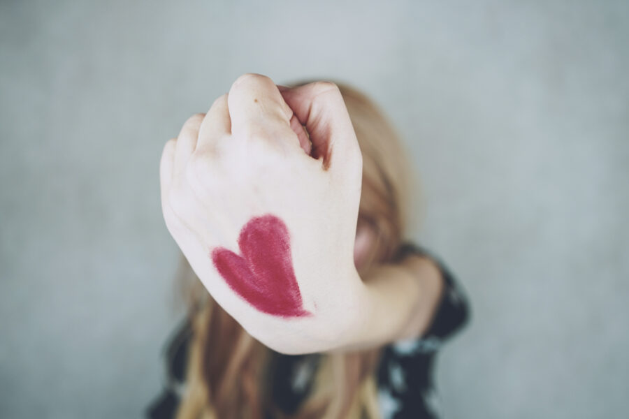 Mujer fuerte con un corazón rojo dibujando en su mano